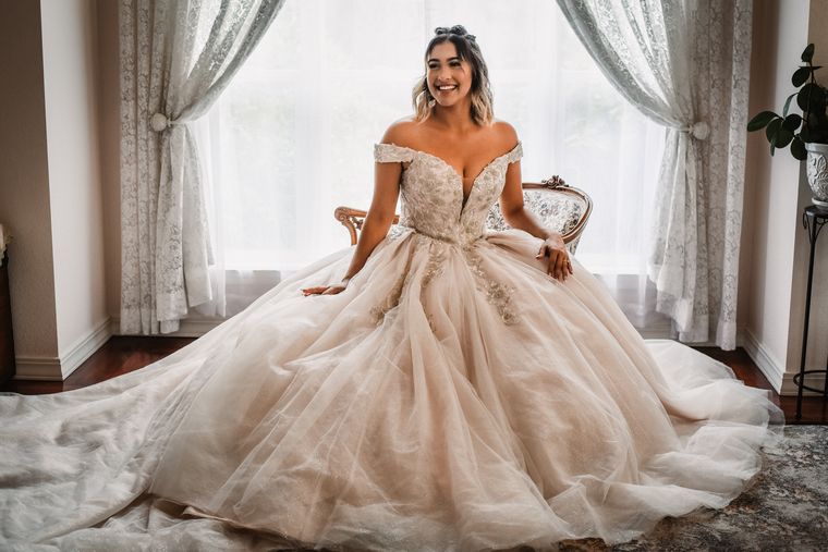 Bride seated by the window in her ballgown in the bride's room at On Collin's Pond