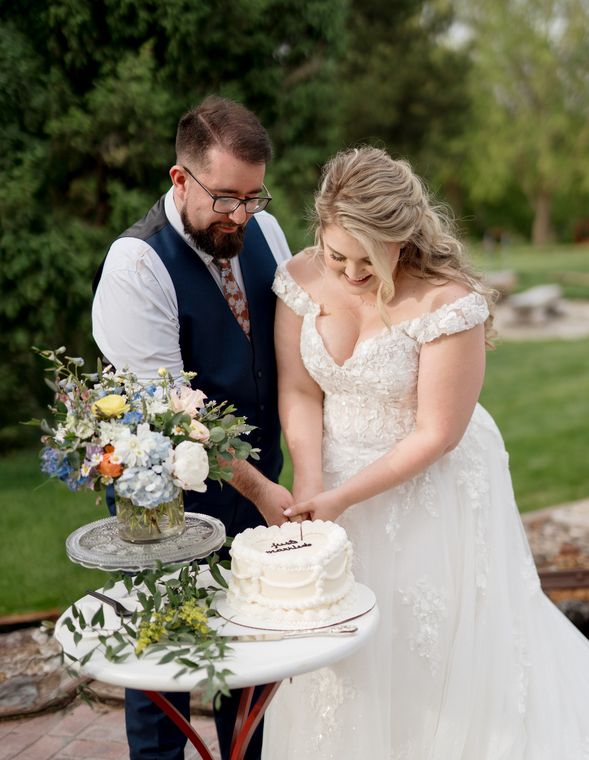 Bride and groom cutting their wedding cake in the gardens at On Collin's Pond, Middleton, Idaho