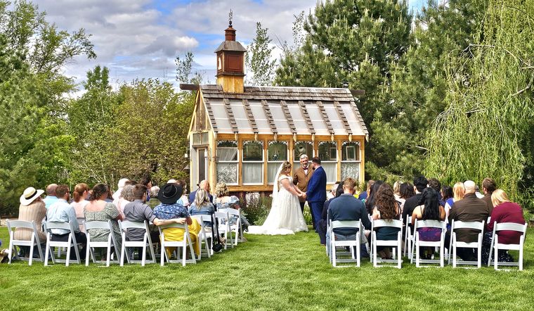 Outdoor wedding ceremony in front of the garden chapel with guests seated on the lawn at On Collin's Pond in Middleton, Idaho