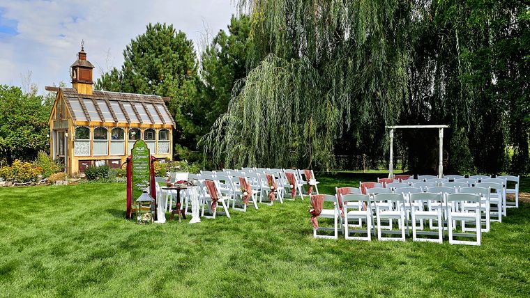Ceremony chairs set out beneath the willow before a garden wedding at On Collin's Pond