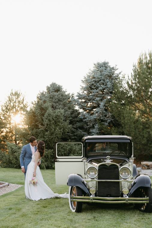 Bride and groom kissing beside the classic car in the gardens at On Collin's Pond