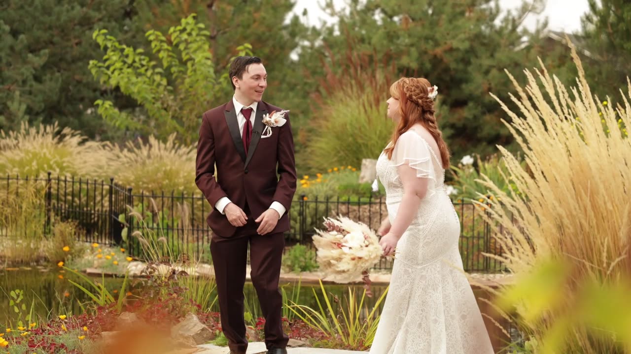 Bride and groom facing each other in the gardens, from the Zoe and Josh wedding film at On Collin's Pond