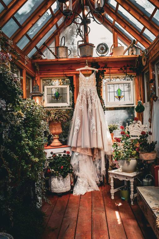 Wedding gown hanging inside the old-world greenhouse at On Collin's Pond