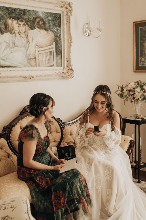 Bride and a guest reading a letter together in the bride's room at On Collin's Pond
