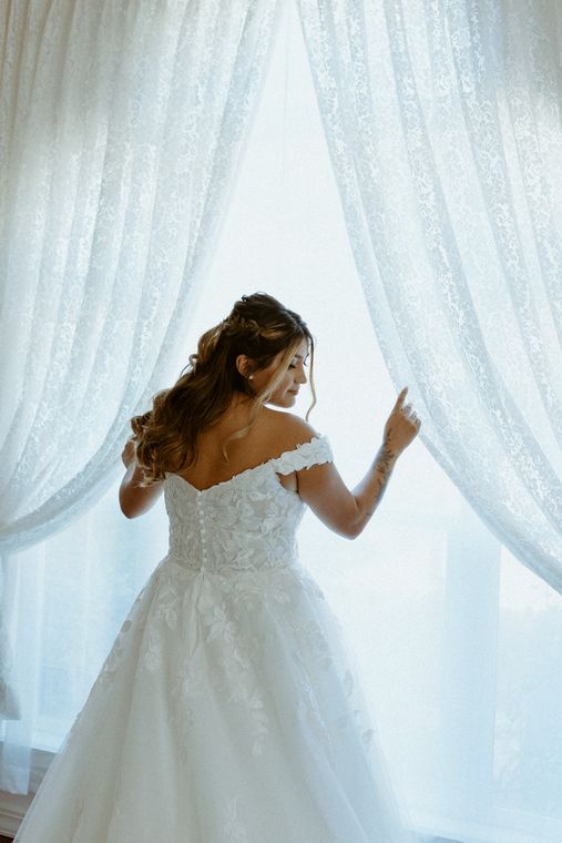 Bride at the window in her gown before the ceremony at On Collin's Pond