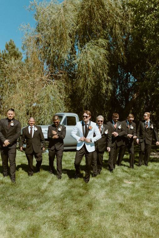 Groom and groomsmen gathered in the tree-lined drive at On Collin's Pond