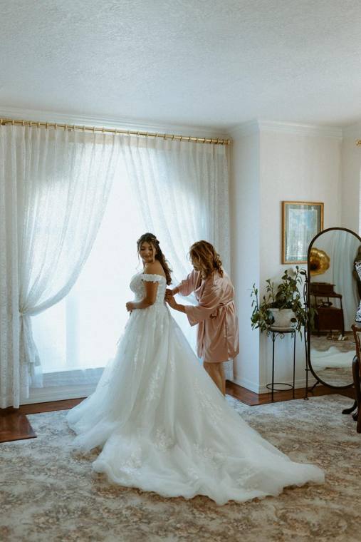 Bride with bridesmaids in golden window light at On Collin's Pond wedding venue