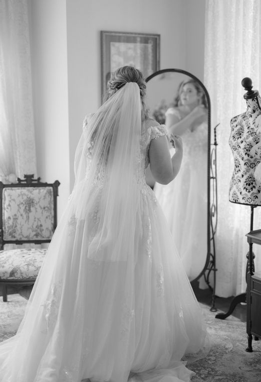 Black and white photograph of a bride with her veil in the bride's room at On Collin's Pond