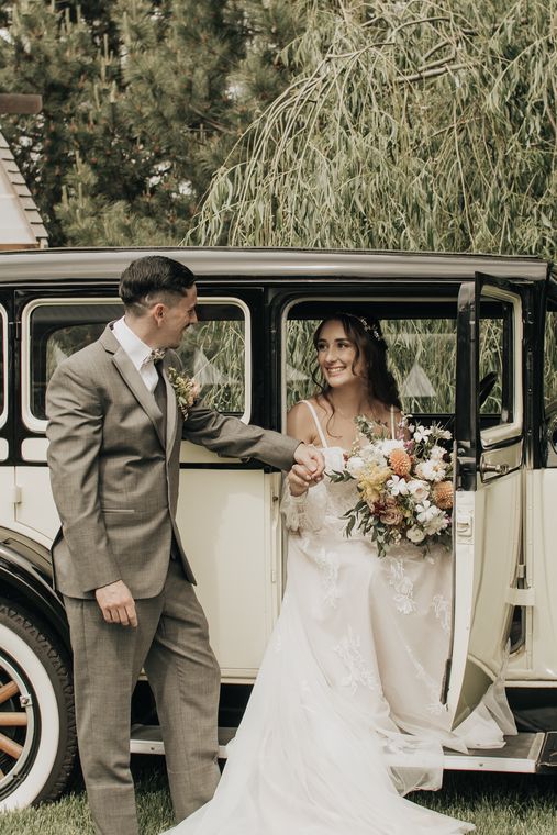 Bride and groom beside the vintage car in the gardens at On Collin's Pond