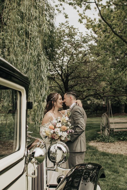 Bride and groom sharing a kiss beside the classic car at On Collin's Pond