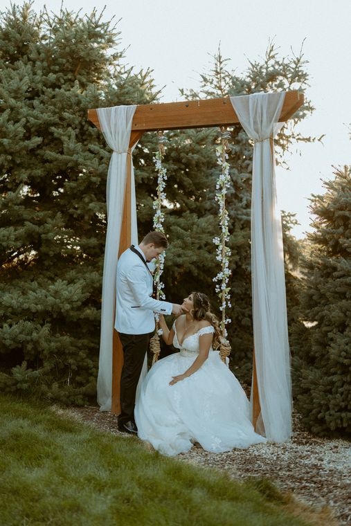 Bride resting at the draped ceremony arch at On Collin's Pond in Middleton, Idaho