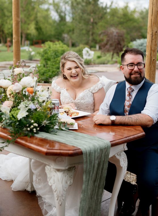 Newlyweds laughing together at the sweetheart table at On Collin's Pond