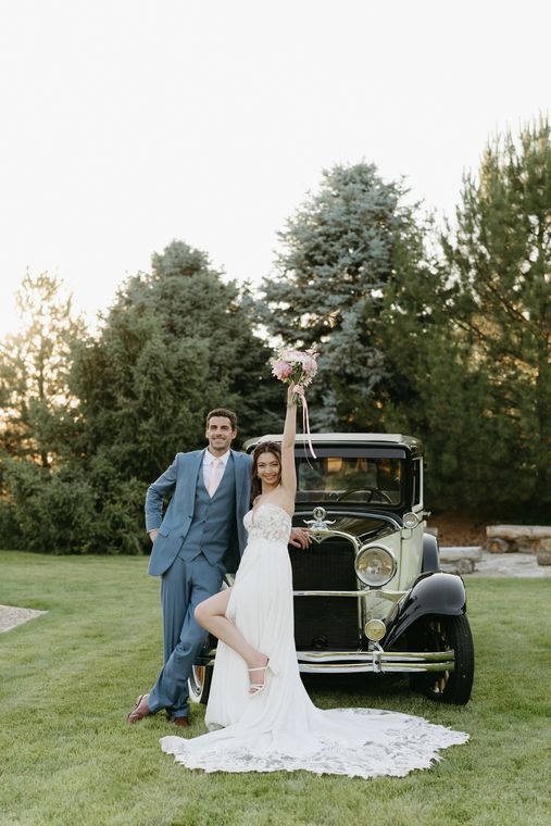 Bride and groom with the vintage car on the lawn at sunset at On Collin's Pond