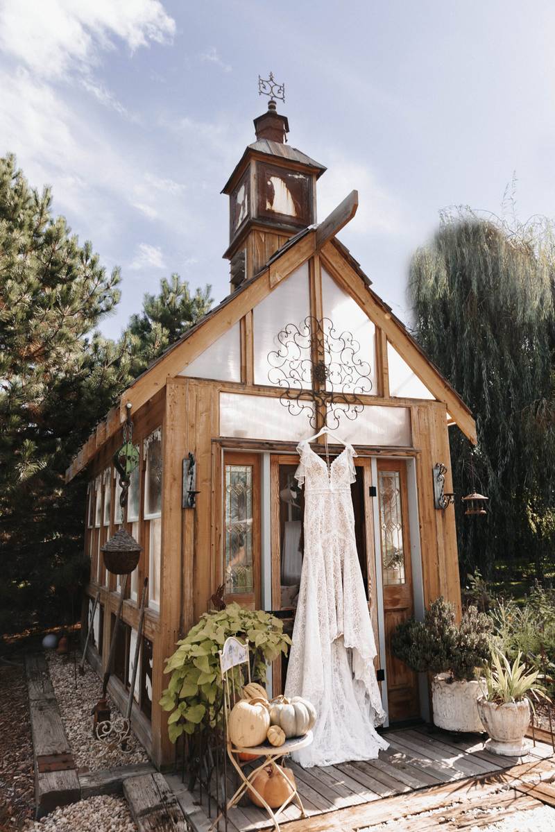 Wedding gown hanging in the greenhouse doorway at On Collin's Pond in Middleton, Idaho