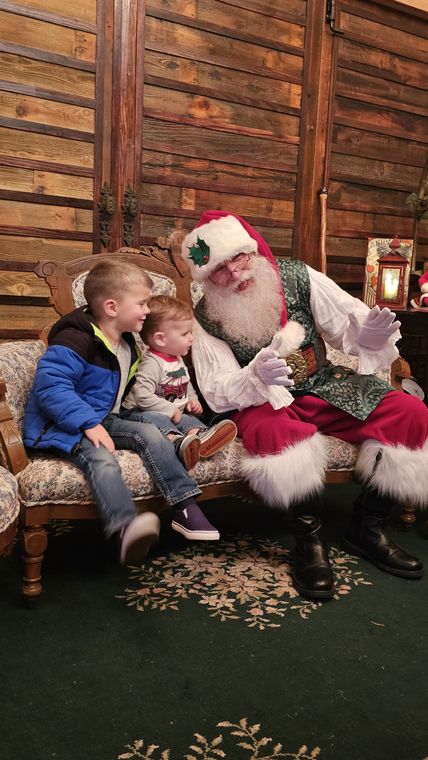 Santa Phil with two children on the settee in the lodge at On Collin's Pond