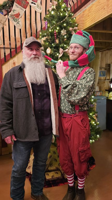 An elf with a visitor beside the Christmas tree at On Collin's Pond