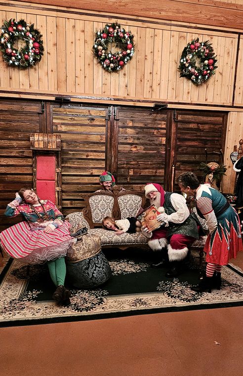 Santa Phil and an elf with a family in the lodge at On Collin's Pond