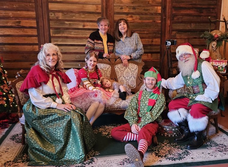 Mrs. Claus, Santa Phil and an elf with a family in the lodge at On Collin's Pond