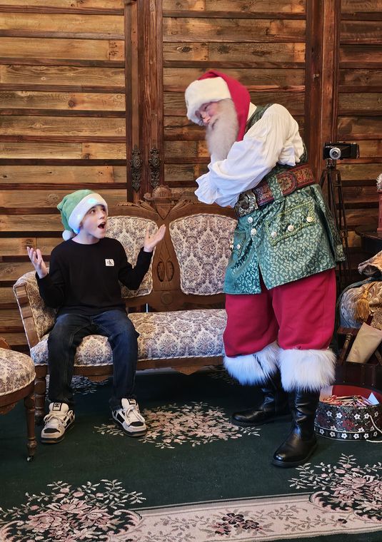 Santa Phil greeting a child on the settee in the lodge at On Collin's Pond