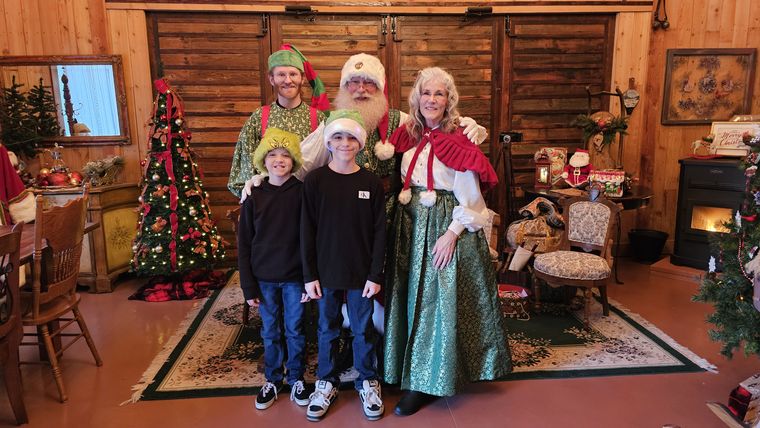 A family photographed with Mrs. Claus and an elf in the lodge at On Collin's Pond