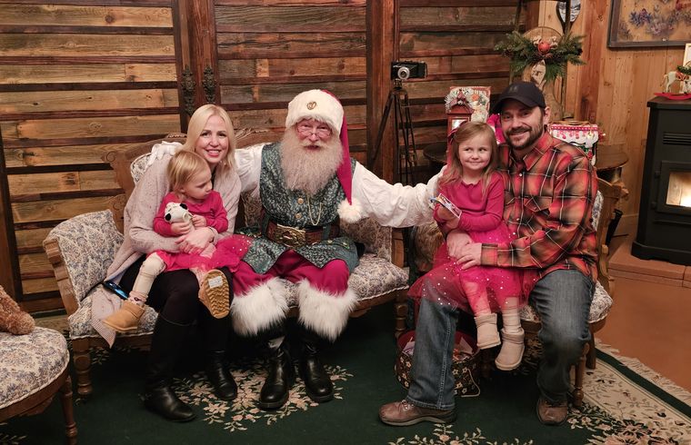 A family photographed with Santa Phil in the lodge at On Collin's Pond