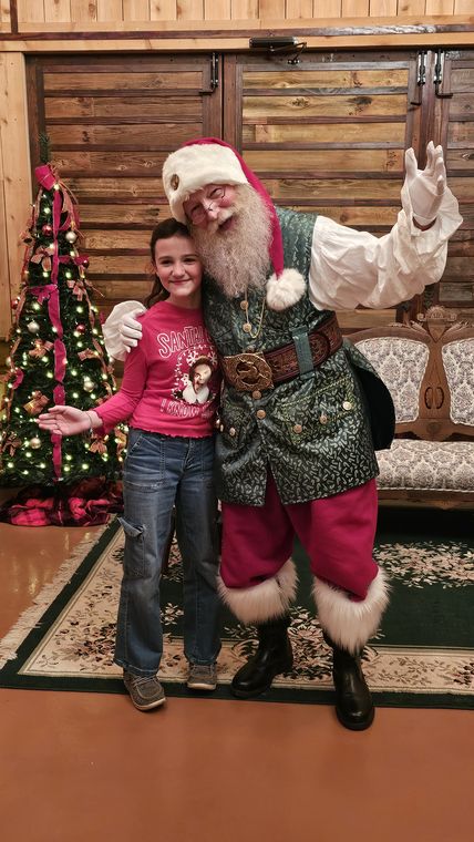 A child beside Santa Phil at the Christmas tree in the lodge at On Collin's Pond