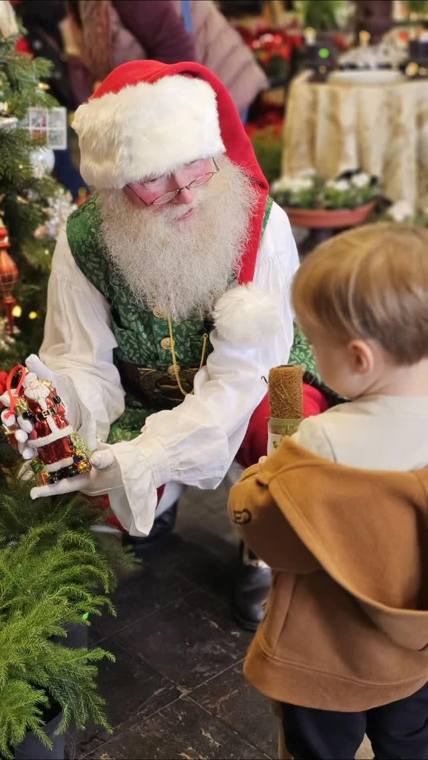 Santa Phil handing a gift to a toddler during a Christmas visit