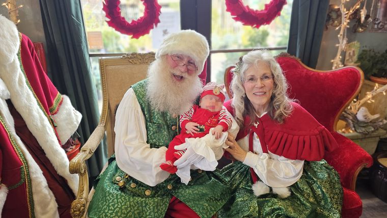 Santa Phil and Mrs. Claus holding a baby at an off-site Christmas event