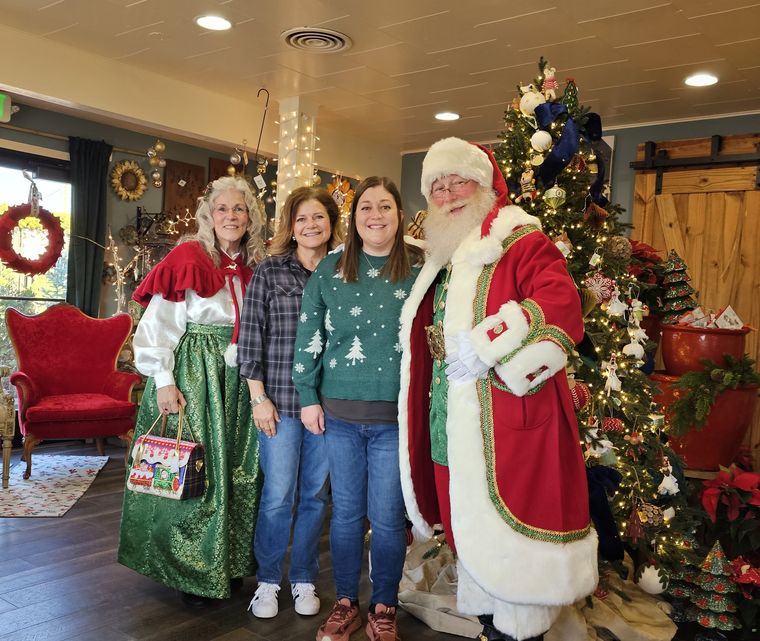 Santa Phil and Mrs. Claus with a family beside the Christmas tree at an off-site event