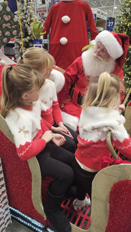Santa Phil in the sleigh with two young visitors at an off-site event