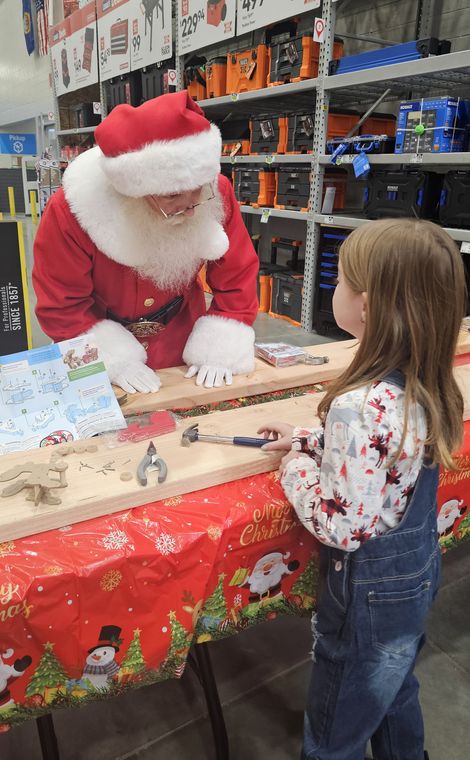 Santa Phil helping a child at the craft table during an off-site event