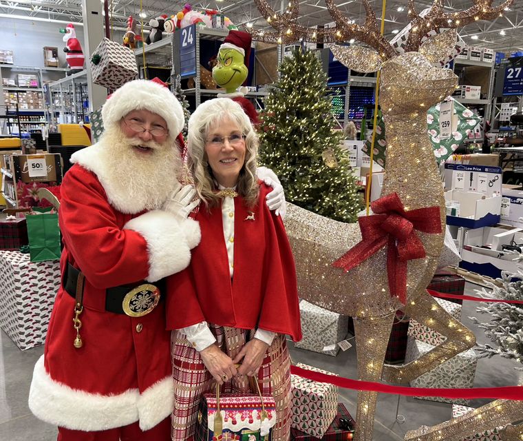 Santa Phil and Mrs. Claus beside the Christmas tree at an off-site holiday event