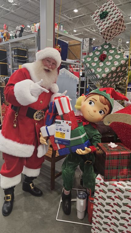 Santa Phil with an elf and a pile of gifts at an off-site Christmas event