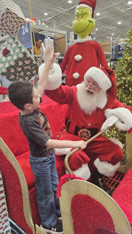 A boy meeting Santa Phil beside the sleigh at an off-site Christmas event