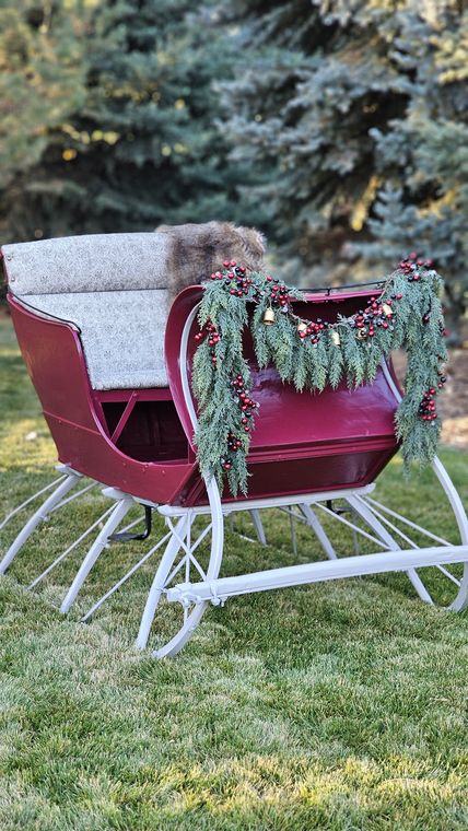 The red sleigh trimmed with garland on the winter grounds at On Collin's Pond
