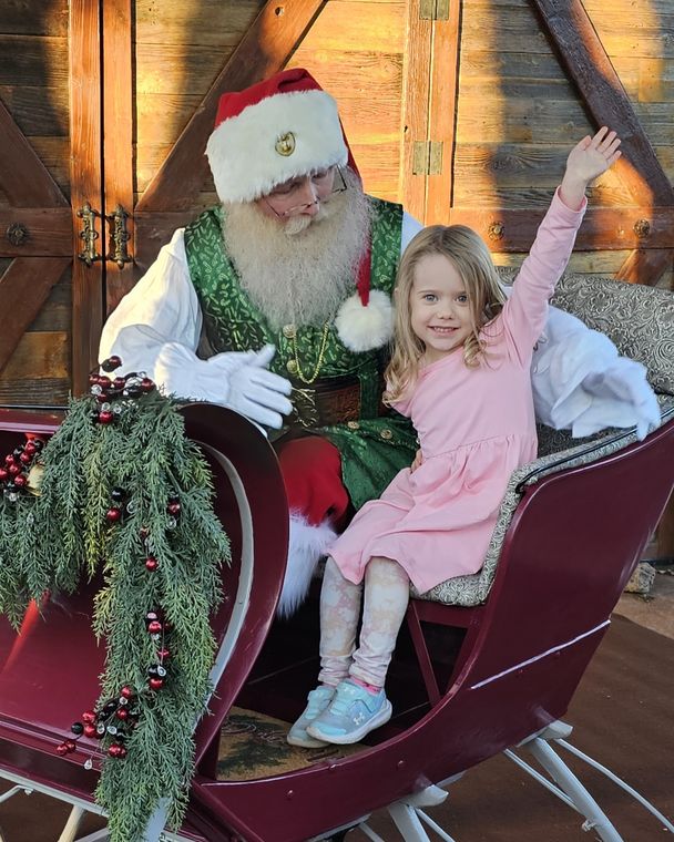 A delighted child riding in the sleigh with Santa Phil at On Collin's Pond