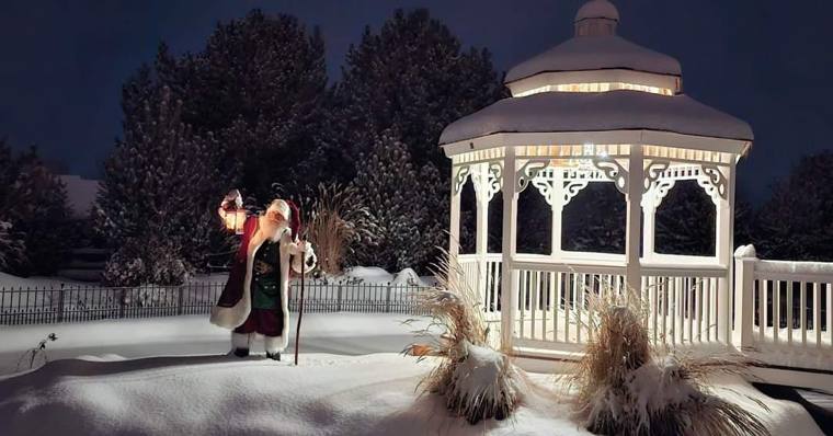 Santa Phil with his lantern beside the illuminated gazebo on a snowy night