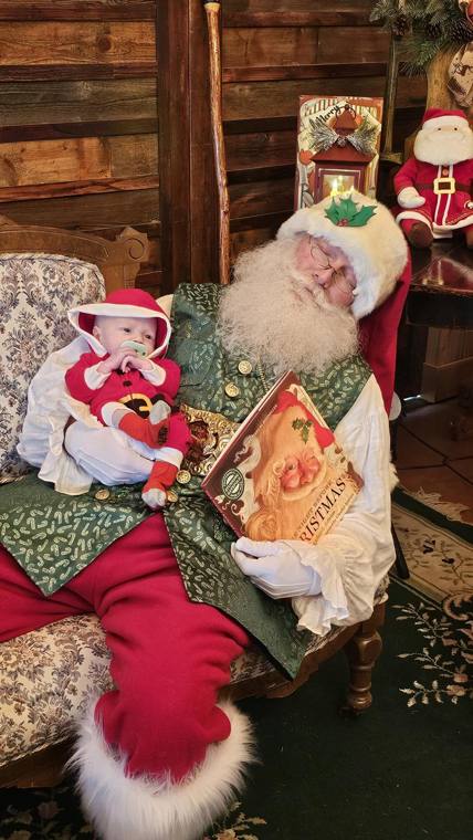 Santa Phil reading The Night Before Christmas to an infant in the lodge