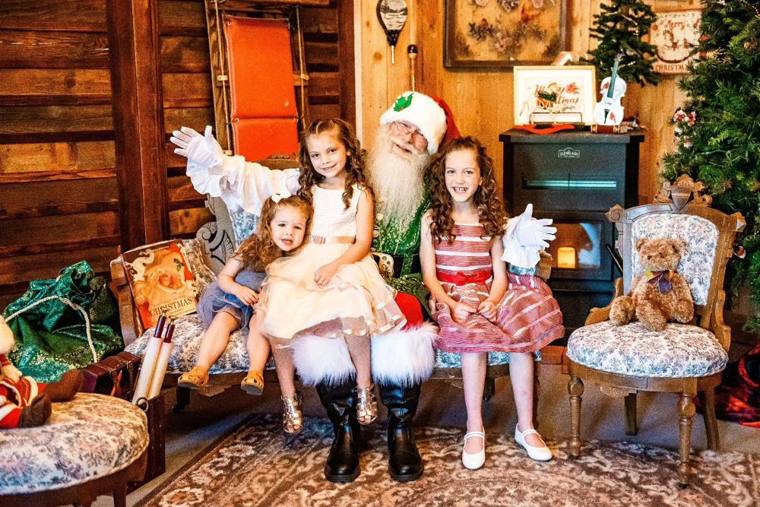 Two young sisters waving beside Santa on the lodge set at On Collin's Pond