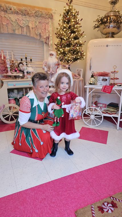 An elf welcoming a child into Chelsea's Sweet Shoppe at On Collin's Pond