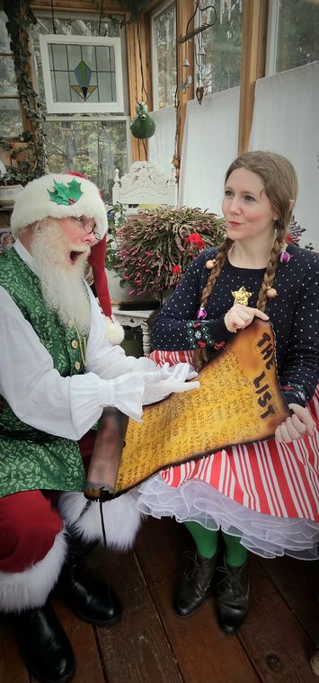 An elf showing a visitor a Christmas stocking in the greenhouse at On Collin's Pond