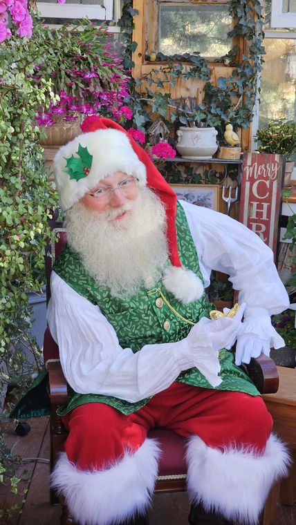 Santa Phil in the greenhouse surrounded by blooms at On Collin's Pond