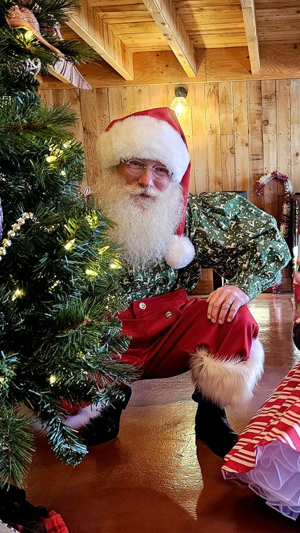 Santa Phil beside the Christmas tree in the lodge at On Collin's Pond