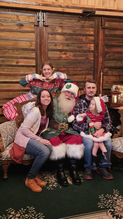 Santa Phil with a family on the settee in the lodge at On Collin's Pond